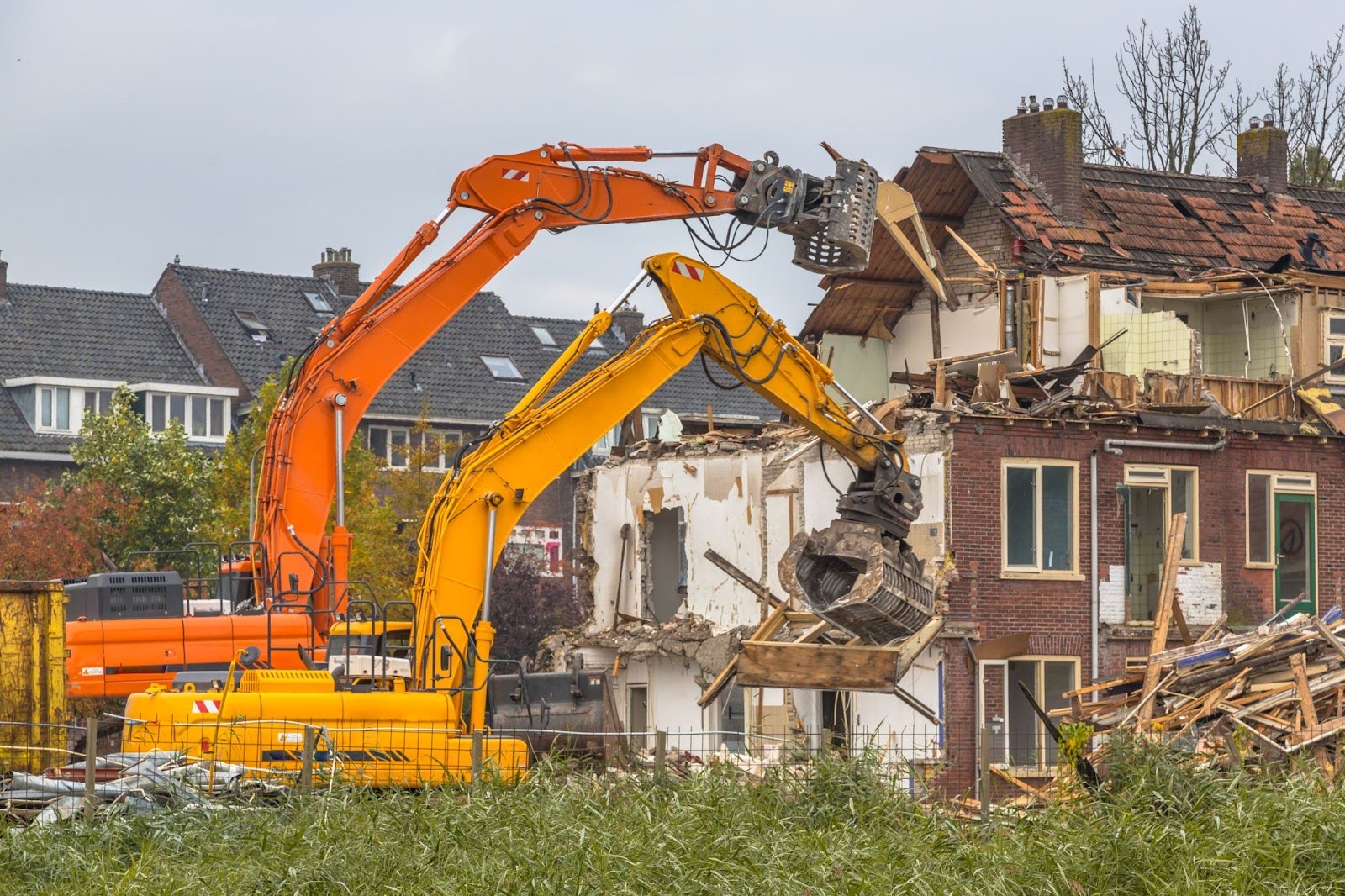 Two large cranes demolish an old house to make way for new construction.