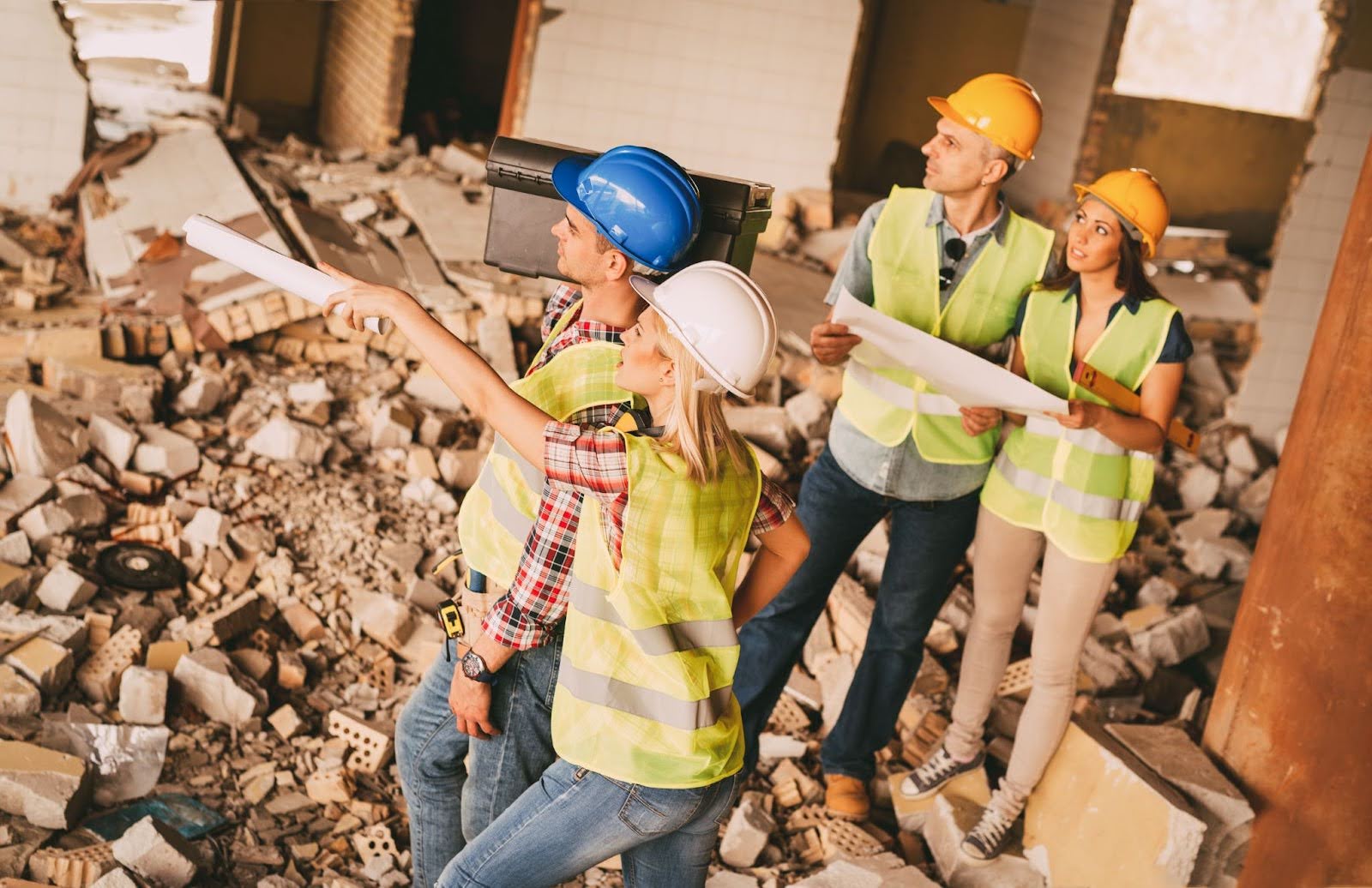 A group of workers are in construction site, looking over a demolition site.