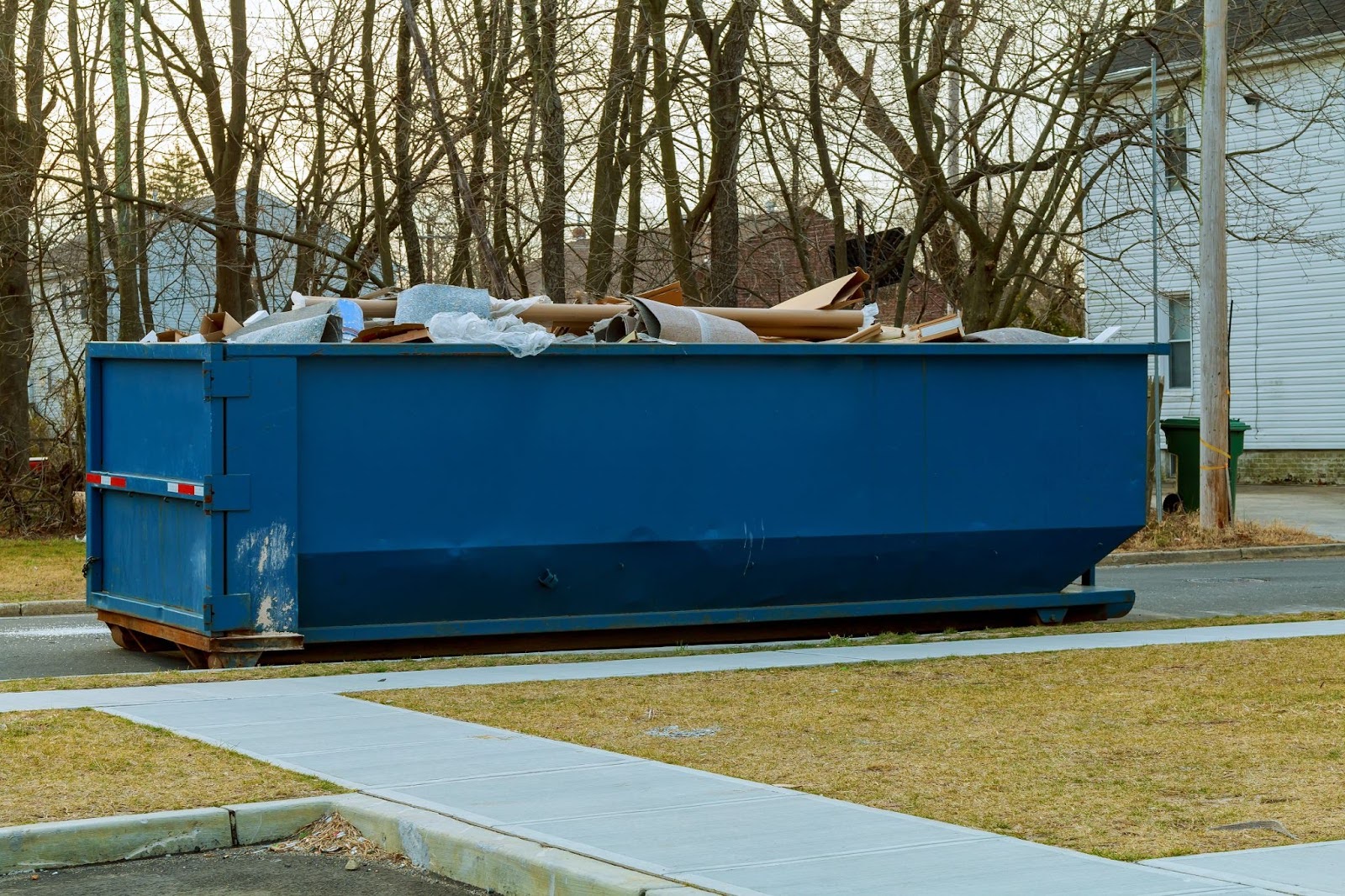 An overflowing dumpster in front of a home.