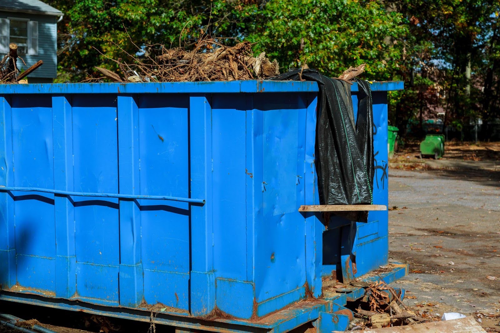 Closeup on a large dumpster rental overflowing with yard waste.