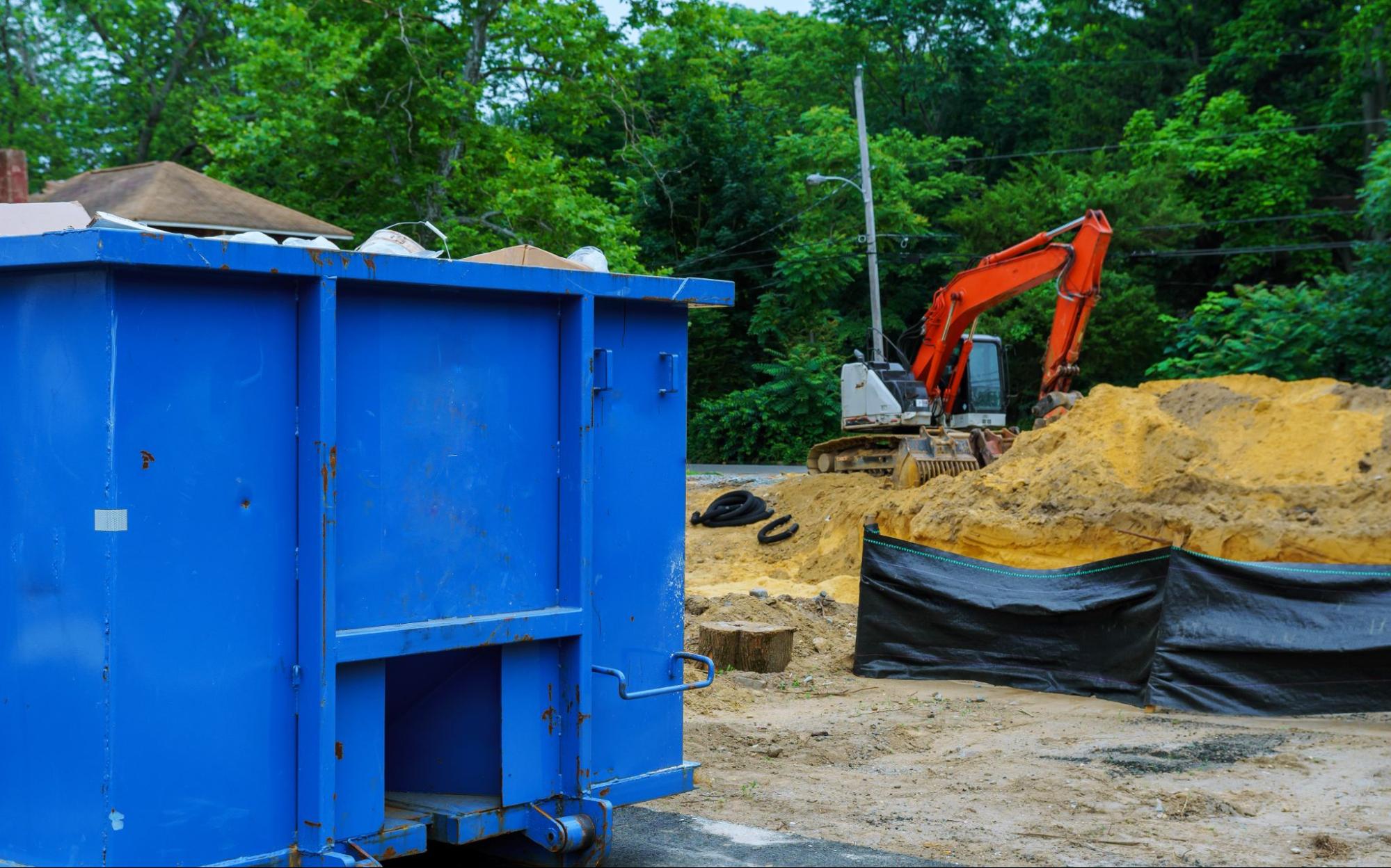 Dumpster next to machinery on a construction site.