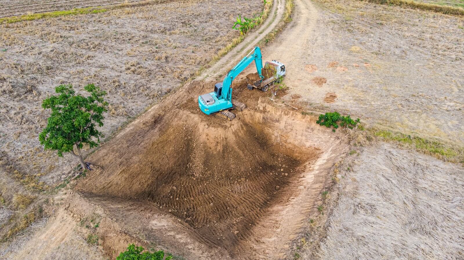Aerial view of an excavator performing land-clearing services on a construction site.