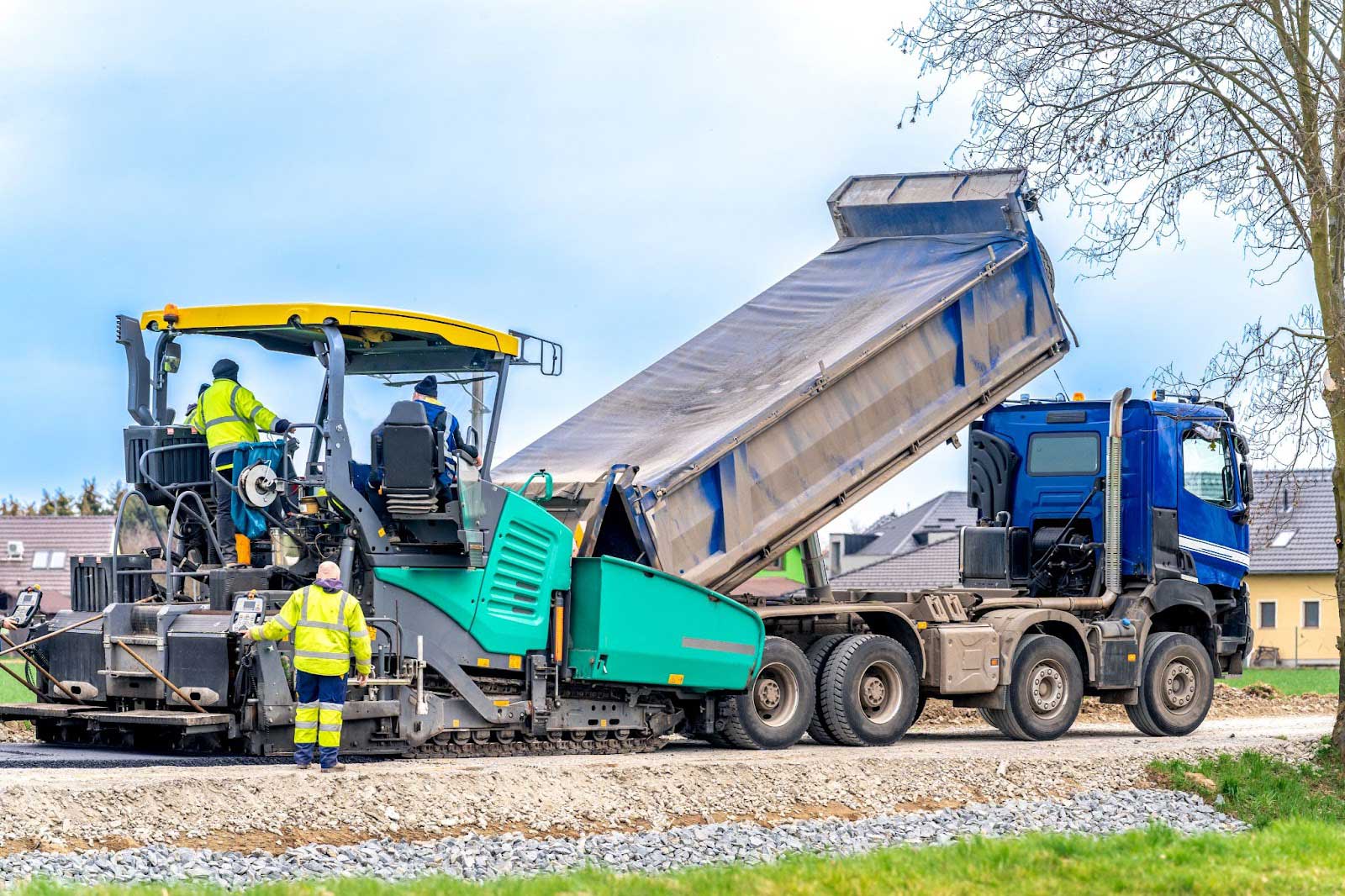 Truck laying gravel during road construction.