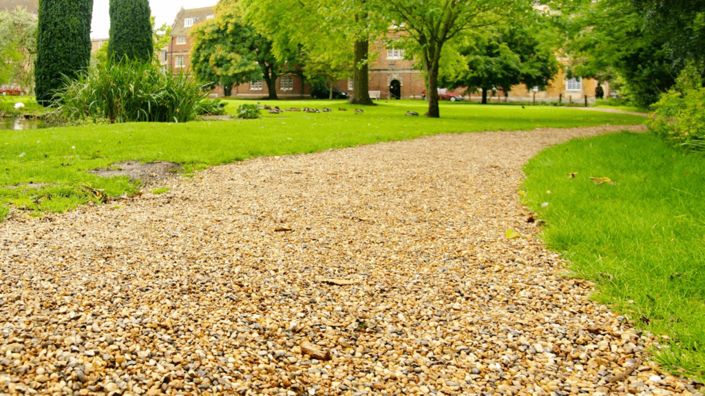 Curved gravel driveway winding through a lush, green college garden.